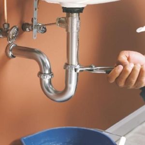 Person adjusting sink pipes with a wrench